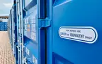 Blaue Container bei Lager-Ein DE GmbH in Schwulper, Detailansicht mit Aufschrift zu Reparaturen.