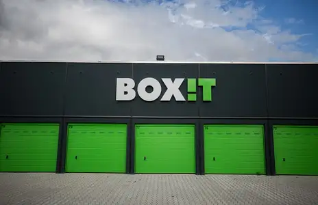 Außenansicht von BOXIT in Dorsten; fünf grüne Rolltore und großes Logo auf dunkler Gebäudefassade unter bewölktem Himmel.