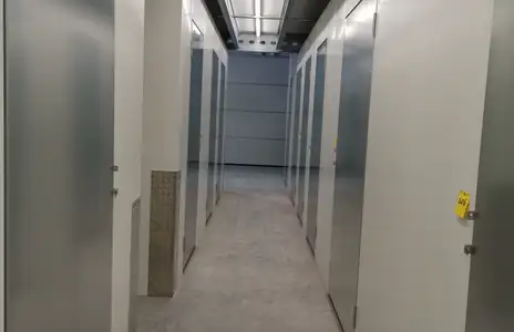 Lagerraum-Gang von Miet Dein Lager Schwabbach mit Reihen weißer Türen und Notausgangszeichen an der Decke.