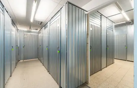 Innenansicht eines Lagerraums bei Storebox Flensburg: Metalltüren in einem Flur mit Deckenbeleuchtung.