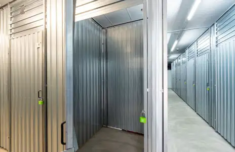 Innenansicht von Storebox: Geöffnete Lagereinheit mit grauen Metallwänden und danebenliegendem Gang in Flensburg.