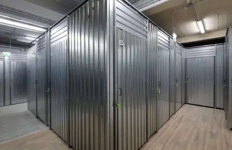 Innenansicht von Storebox in Freiburg: Metalllagerabteile in einem Gang mit Holzboden und Beleuchtung.