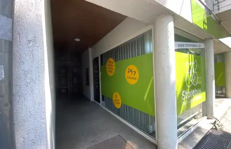 Außenansicht eines Storebox-Standorts mit grünem Banner und Logos, zeigt Eingangsbereich und 24/7-Zugangsangebot.