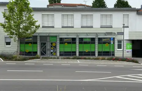 Außenansicht des Storebox-Gebäudes in Lindau mit Schaufenstern, Parkplätzen und erkennbaren Beschilderungen.