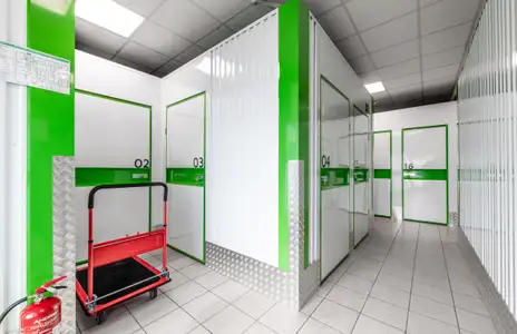 Innenansicht von Storebox: Flur mit nummerierten Lagerräumen, Transportwagen und Feuerlöscher.