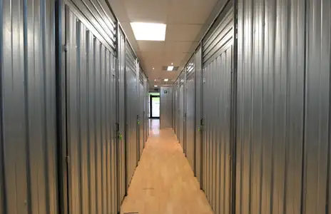 Gang eines Lagerraums mit metallenen Türen bei Storebox in Osnabrück. Heller Boden und Deckenbeleuchtung erkennbar.