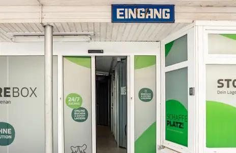 Eingang von Storebox in Stade mit Glasfassade und Schildern wie Eingang und Schaffe Platz. Schneebedeckter Boden.