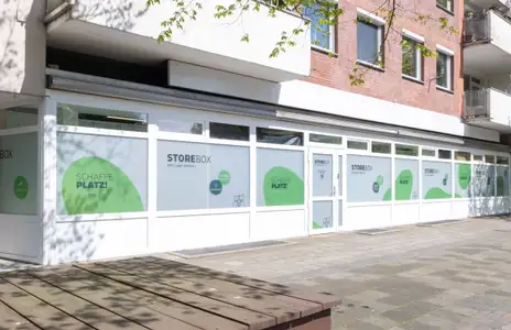 Storebox-Außenansicht in Wilhelmshaven mit großen Fenstern und grüner Beschriftung auf weißem Hintergrund.