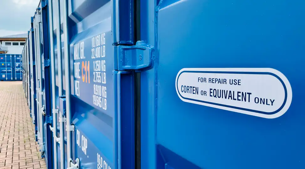 Blaue Container bei Lager-Ein DE GmbH in Schwulper, Detailansicht mit Aufschrift zu Reparaturen.